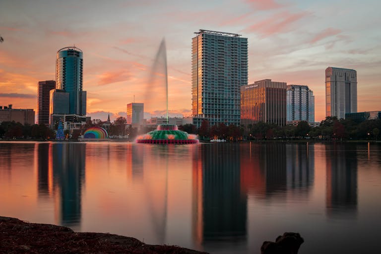 Beautiful view of Orlando skyline during sunset with Lake Eola fountain reflecting on the water.