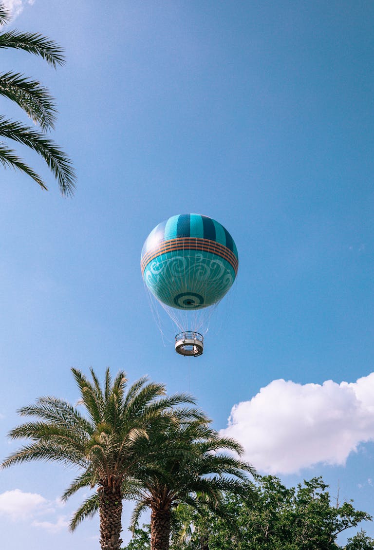 Colorful hot air balloon floating above palm trees at Disney Springs.